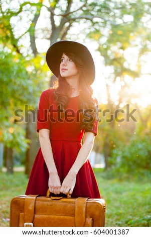 photo of beautiful young woman with suitcase standing in the park