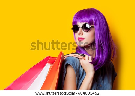 photo of beautiful young woman in wig with shopping bags on the wonderful yellow background