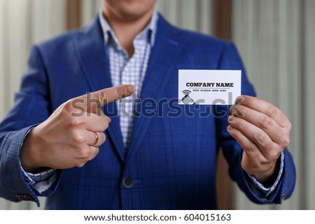Businessman holding visit card. Man showing blank business card with phone icon. Person in blue suit points a finger. Mock up design.