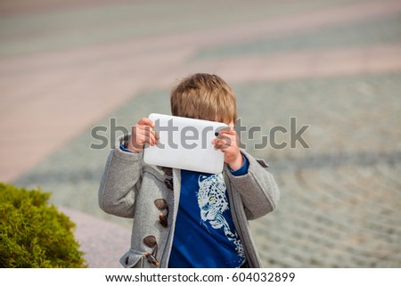 Little boy uses a tablet outdoors. Digital generation next
