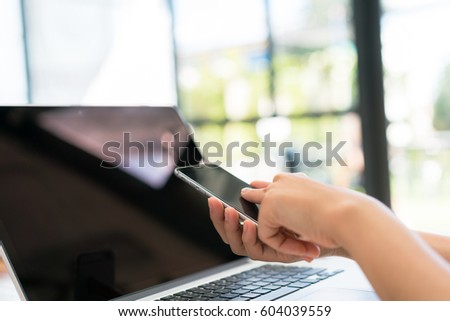 Closeup of business woman hand typing on laptop keyboard with mobile phone