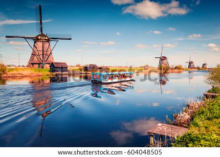 Famous windmills in Kinderdijk museum in Holland. Sunny spring morning in countryside. Colorful outdoor scene in Netherlands, Europe. UNESCO World Heritage Site. Artistic style post processed photo.