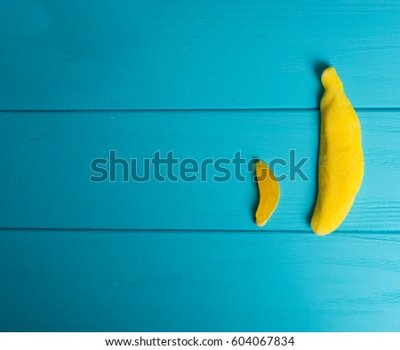 Jelly candies in the form of a big and small gummy bananas on wooden turquoise table
