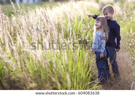 Little boy and little girl standing holding hands looking on horizont. Rear view.