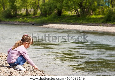 Little girl playing near river