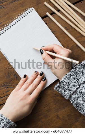 A woman with a beautiful manicure draws in a notebook