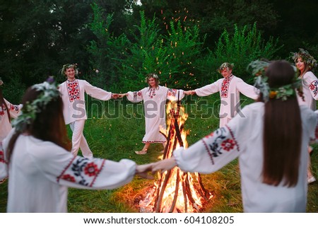 Midsummer. Young people in Slavic clothes circle dance around a bonfire in the forest.