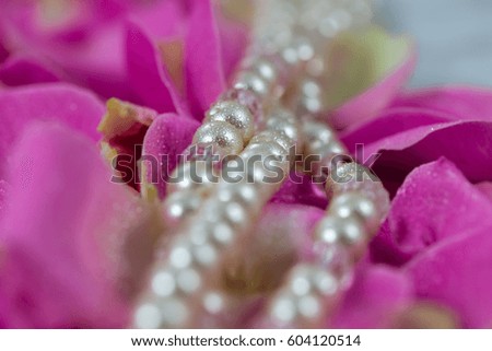 A bead chain lies on rose petals
