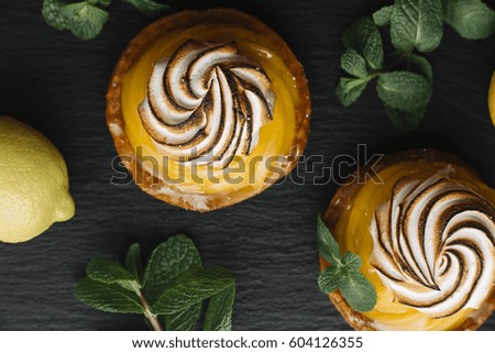 Lemon pie on the table with citrus fruits. Traditional french sweet pastry tart. Delicious, appetizing, homemade dessert with lemon cream. Copy space, closeup. Selective focus. Toned. Top view