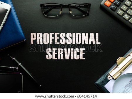 Black chalkboard with business accessories (notepad, magnifying glass, fountain pen, tablet, phone, glasses and calculator) and text PROFESSIONAL SERVICE. Top view.