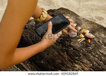 Woman is taking pictures of seashells on the beach