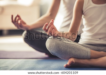 Cropped image of young woman and her little daughter doing yoga together at home Royalty-Free Stock Photo #604201109