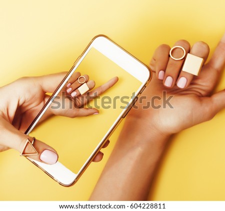 womans hand taking picture of her new manicure with fashion jewellery on her phone, girls stuff concept 