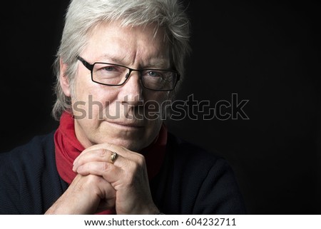 Man male portrait close up thinking looking in to camera with spectacles with hands under chin black background