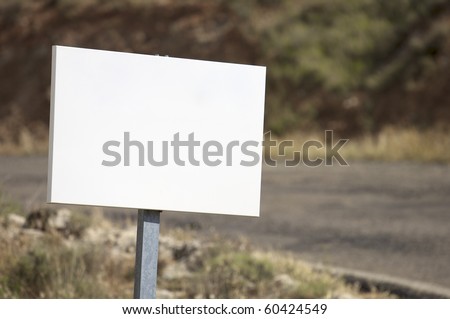 view of a rectangular white sign at the edge of a road