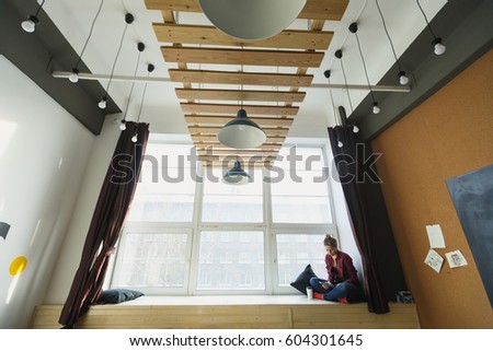 Business woman holding the tablet and wearing glasses. Woman sitting and lies near the window. Hipstar style.