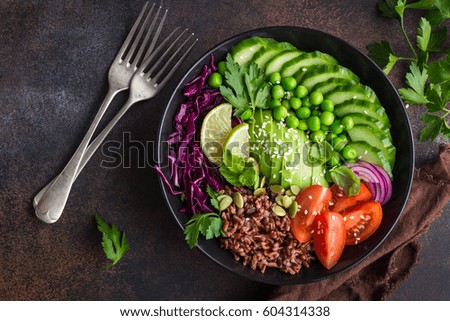 vegan lunch bowl. Avocado, red rice, tomato, cucumber, red cabbage, green peas vegetables salad. Top view