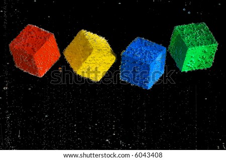 Four brightly colored cubes floating in a clear bubbly liquid on a black background.