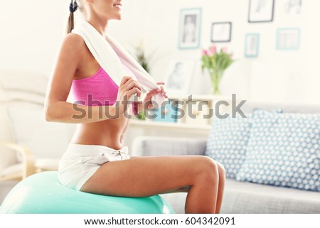 Picture of young woman with sports equipment at home.