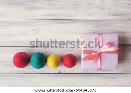 Gift box with painted eggs over wooden background