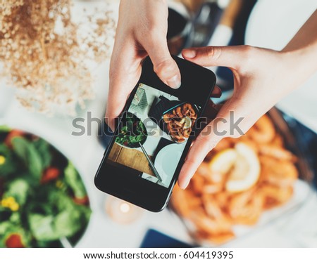 Top view shot of female hands taking a picture of food, young hipster girl making a photo of tasty mediterranean food table