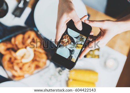Top view image of female hands taking a picture of homemade food by smartphone, hipster girl making a photo of table with food on cellphone