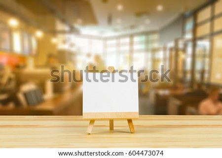 Easel with blank canvas on wooden table,billboard on wood desk top with supplied bokeh background,Template mock up for montage of display your product.vintage color