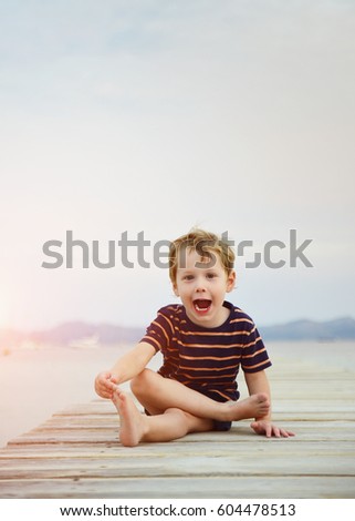 Little blond boy having fun on the beach in summer