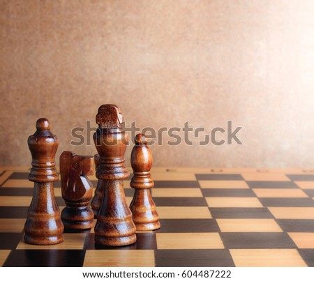 Wooden chess board with figures on table and old wall