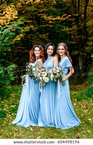 Beautiful cute girls are walking in the park. Three bridesmaids posing for a photographer. Beautiful green background. Nature.