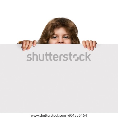 Happy little boy hiding behind blank advertising banner with copy space