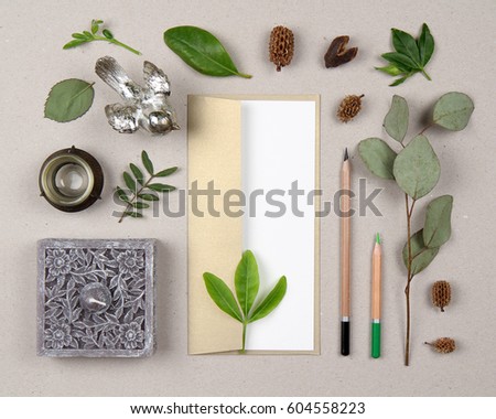 blank card mock up, artwork paper, gold envelope, pencils, rustic decorative elements, natural green leaves. Botanical art background. View from above