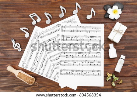 Composition of music sheets and spa supplies on wooden background