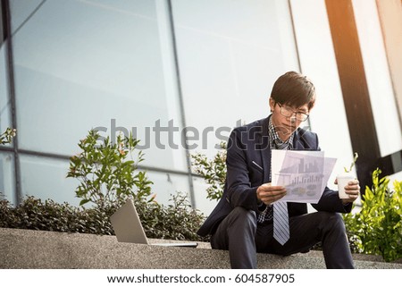 Looking for the right document. Confident young business man in formal wear taking the documents out of briefcase while sitting outdoors.