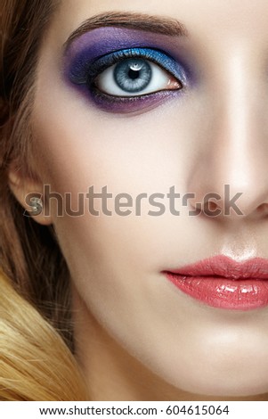 Closeup shot of female half face with  and violet and blue eyes makeup