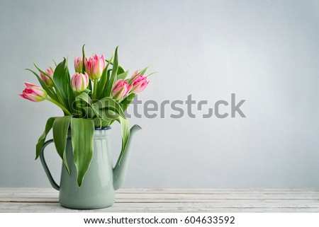 Bouquet of pink tulips in vase over  blue background 
