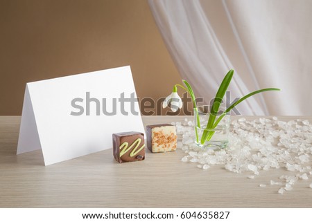 Greeting card with snowdrop and chocolate on the table. Spring flower.