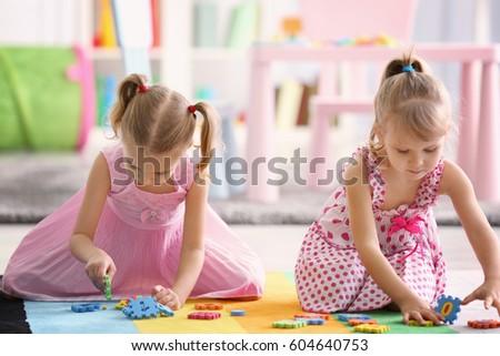 Adorable little sisters playing on floor at home