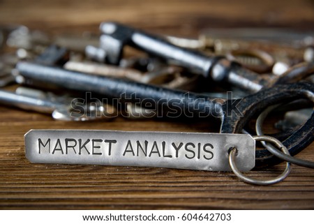 Photo of key bunch on wooden board and tag with letters imprinted on clean metal surface; concept of MARKET ANALYSIS