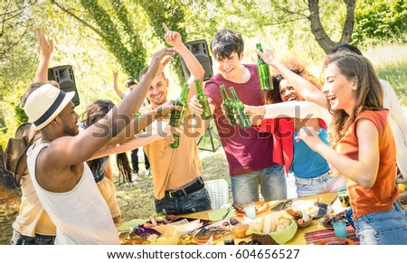 Young multiracial friends toasting beer at barbecue garden party - Friendship concept with happy people having fun at backyard summer camp - Food and drinks fancy dinner with dj music set outdoors 
