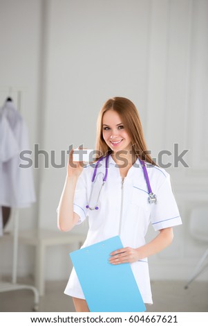 Medical doctor showing business card sign, blank with copy space for text or design. Woman medical professional.