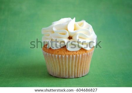 Cupcake with whipped cream on green background. Picture for a menu or a confectionery catalog.