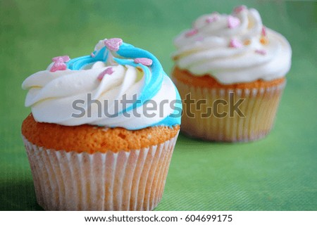 Cupcakes with whipped cream and pink confectionery sprinkling In the form of hearts on green background. Picture for a menu or a confectionery catalog.