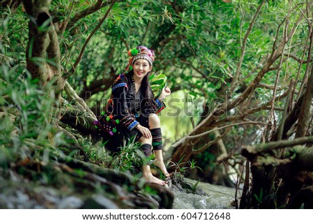 Beautiful girl wearing beautiful traditional red costumes clothes and silver coins on headdress in hill tribe minority village at northern Thailand on the green forest background