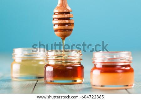 Honey in jar with honey dipper on blue background healthy food