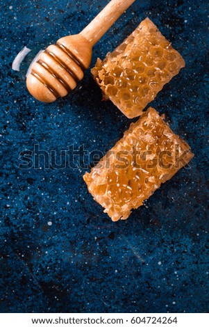 fresh honeycomb with a wooden dipper dripping honey on a dark blue background with copy space