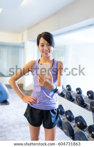 Woman taking selfie in front of mirror in gym