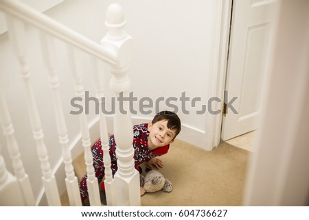 A boy sitting on the stairs, looking upwards and grinning