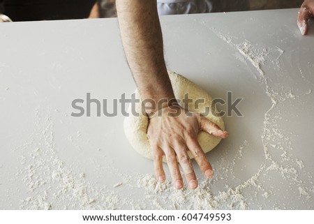 Close up of a baker kneading and shaping bread dough into a ball