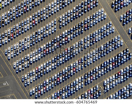 Aerial view of a car distribution centre, new cars parked in rows on a lot ready for sale,